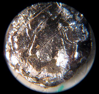 アメリシウム241の線源を顕微鏡で観察した写真。部品全体が純アメリシウムの塊という意味ではありません。